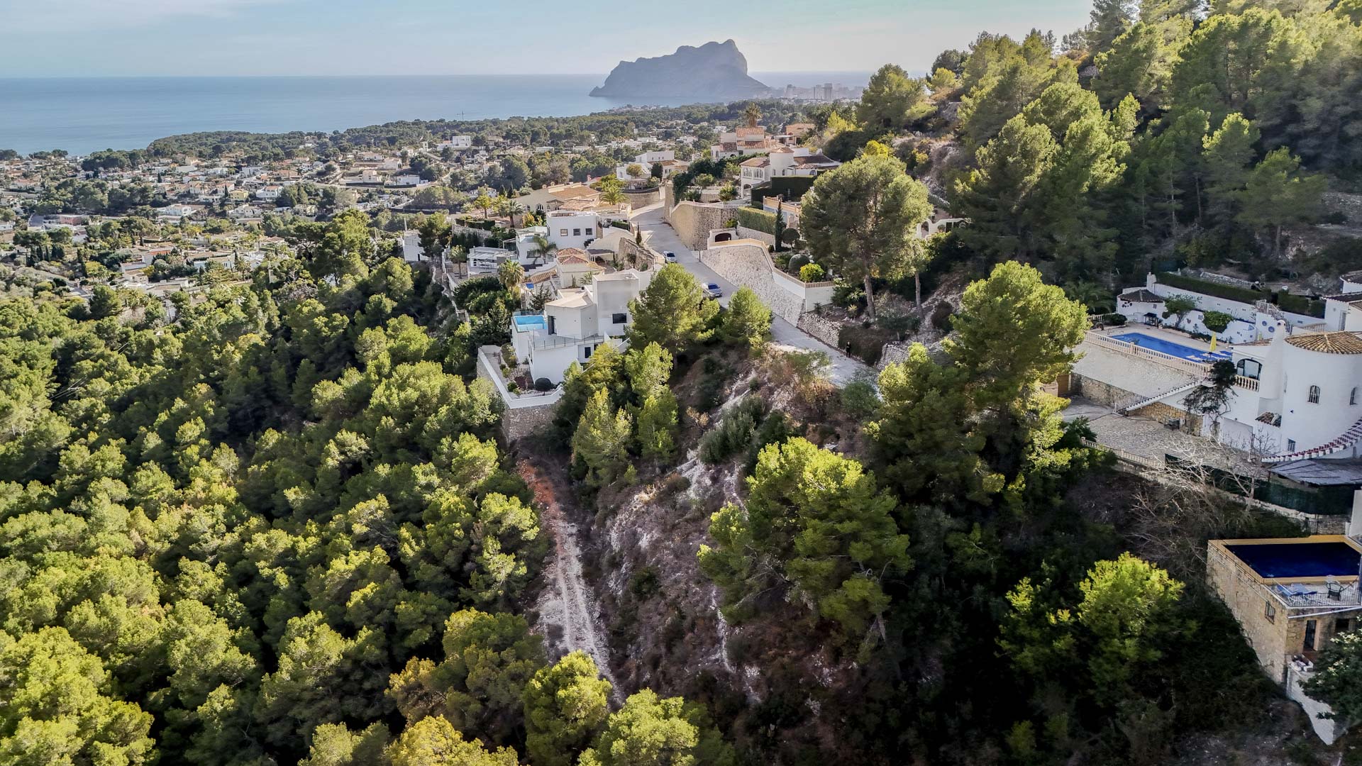 Vue aérienne du quartier résidentiel de Benissa, soulignant la proximité du Peñón de Ifach et de la vaste zone verte protégée entourant les parcelles.