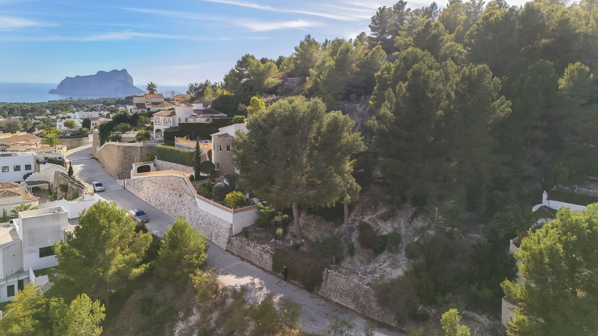 Vue aérienne du terrain surélevé à Benissa, soulignant son environnement boisé de pins et ses vues panoramiques sur la mer et le Peñón de Ifach.