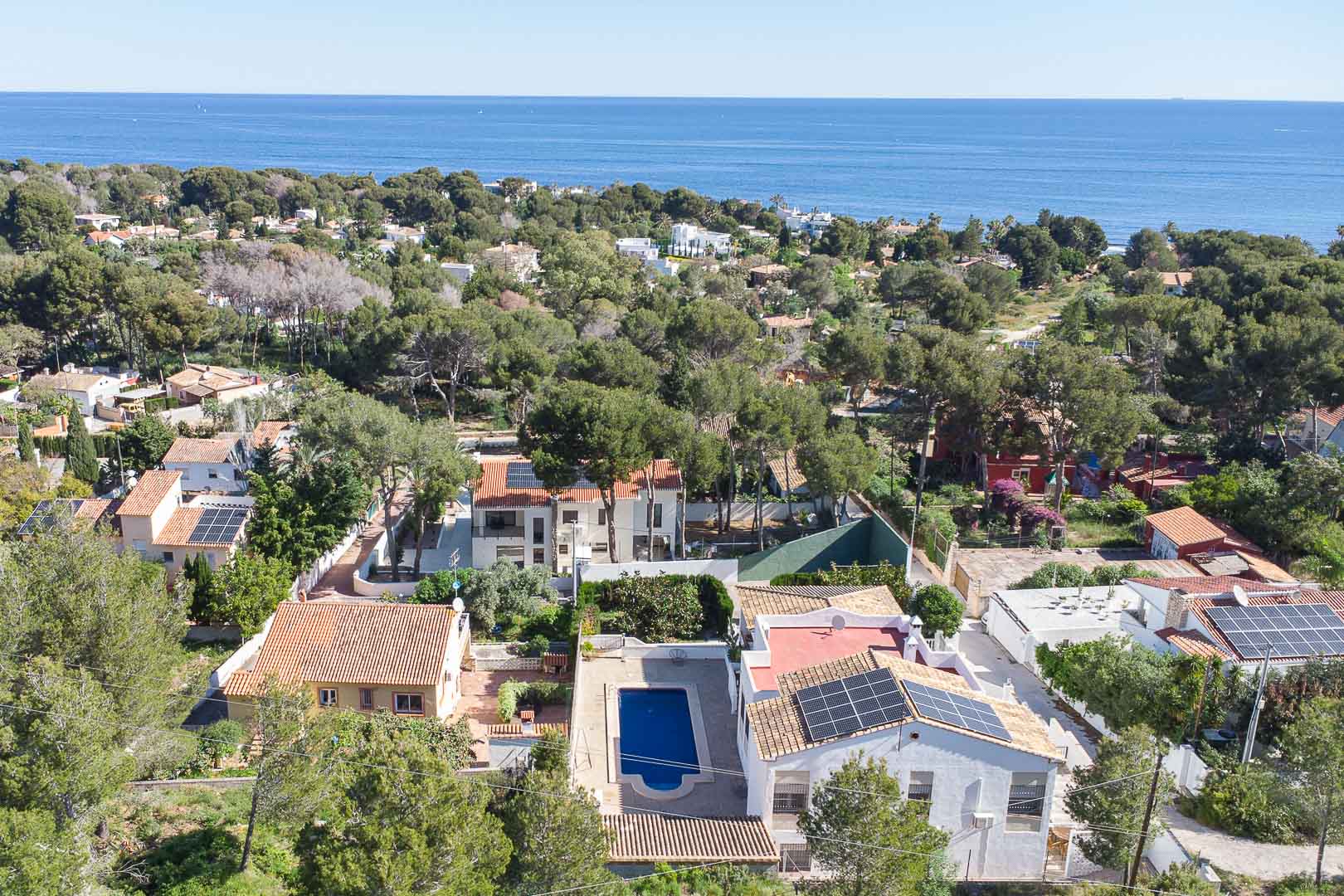 Vue aérienne de la villa à Las Rotas, montrant la piscine privée, les panneaux solaires et l'environnement boisé avec vue sur la mer.
