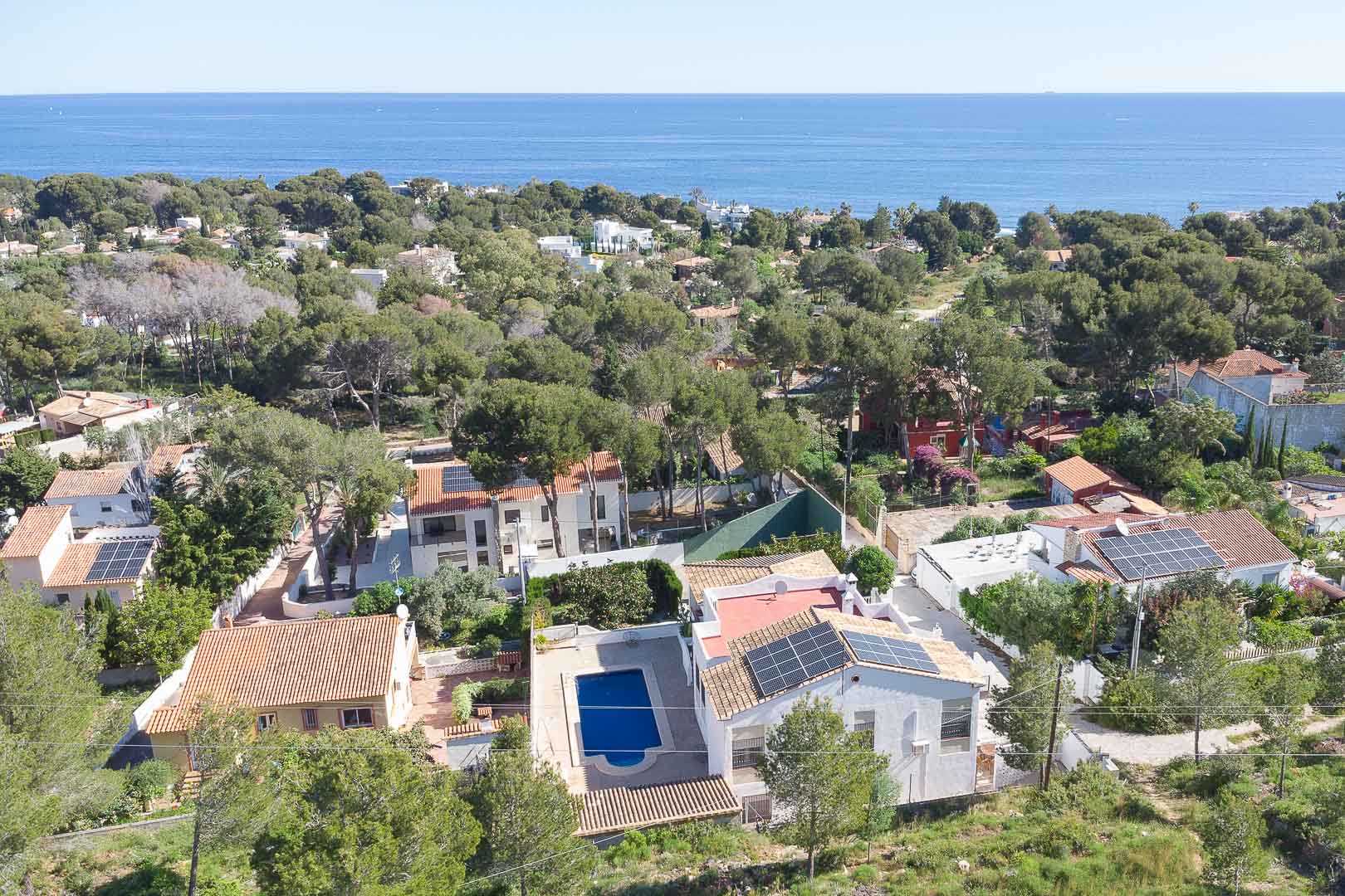 Vue aérienne de la villa avec piscine privée et panneaux solaires, nichée dans une pinède à Las Rotas offrant un panorama sur la mer Méditerranée.
