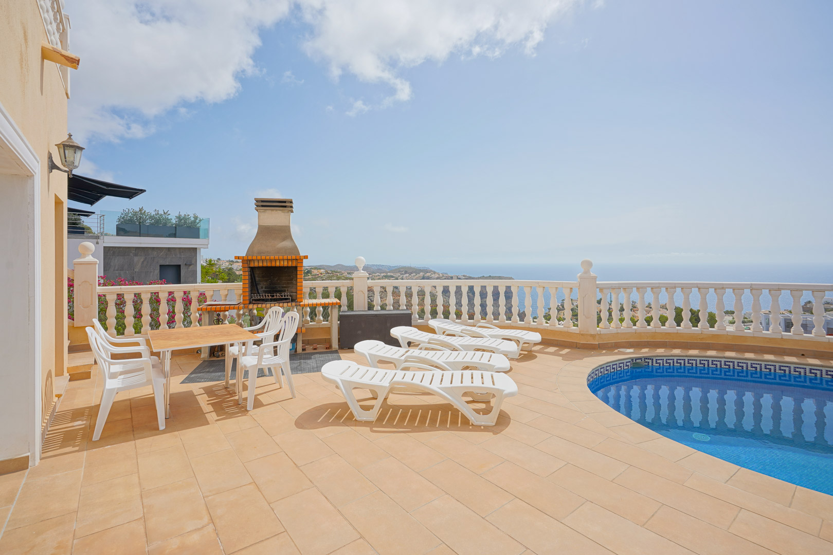 Terrasse extérieure avec piscine, barbecue en brique et chaises longues. L'espace offre une vue dégagée sur la mer Méditerranée et les falaises.