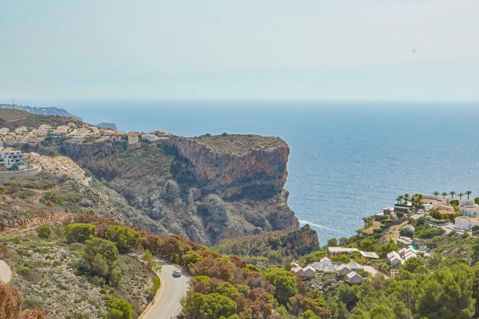 Vue panoramique depuis Cumbre del Sol sur les falaises et la mer Méditerranée, avec la route côtière serpentant à travers la végétation locale.