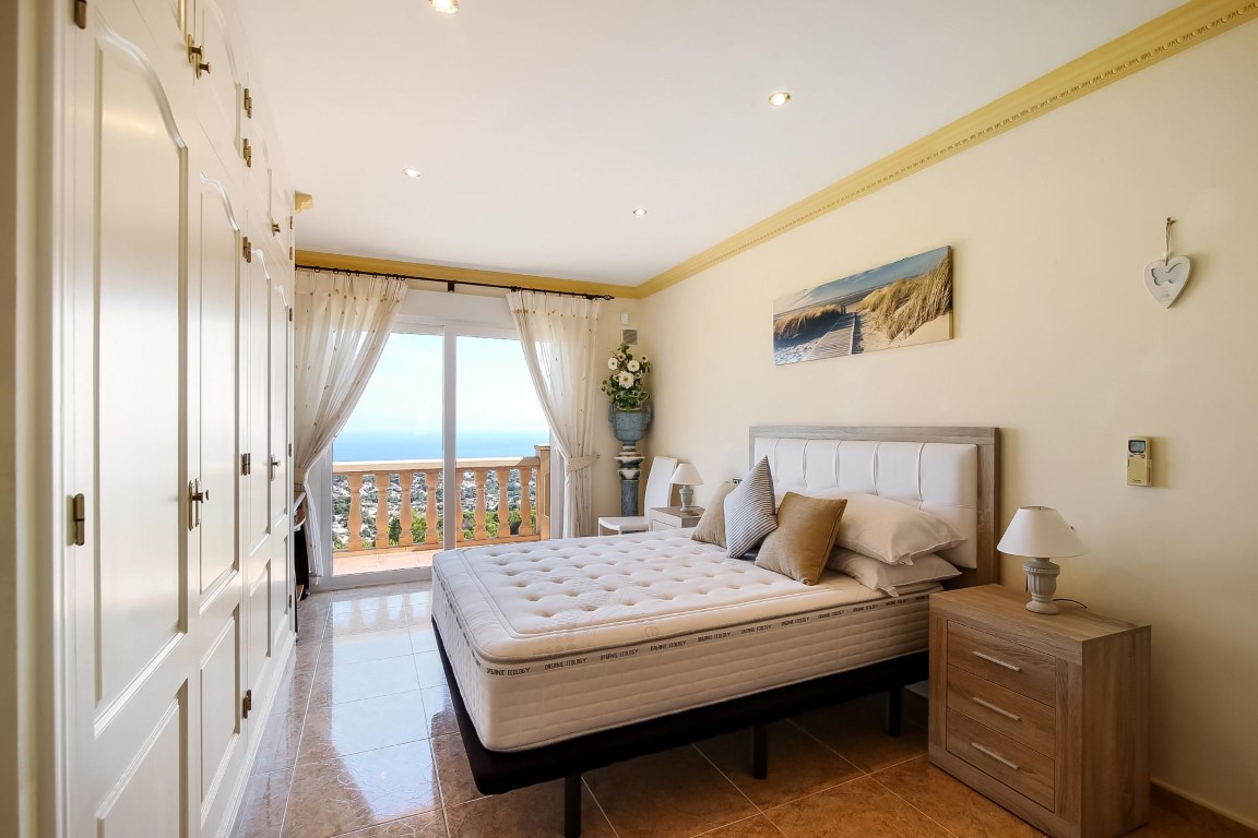 Chambre principale avec placards intégrés, éclairage encastré et accès direct à une terrasse privée surplombant la mer.