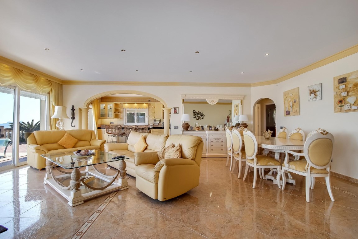 Salon et salle à manger à aire ouverte avec sols en carrelage poli, mobilier classique de couleur crème et une arche élégante menant à la cuisine.