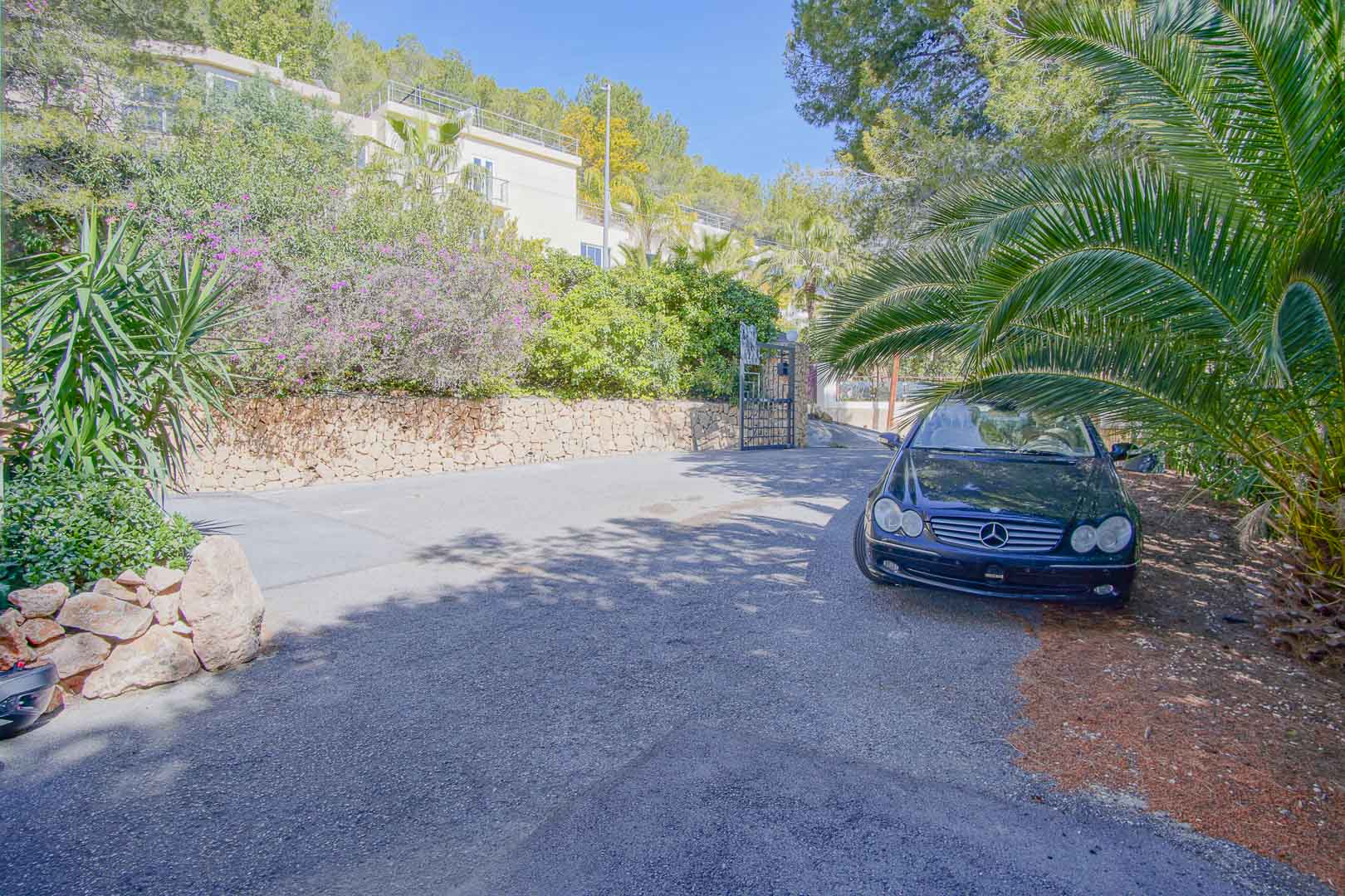 Vaste espace de stationnement extérieur pavé, entouré de murs en pierre naturelle et d'une végétation méditerranéenne luxuriante assurant l'intimité.