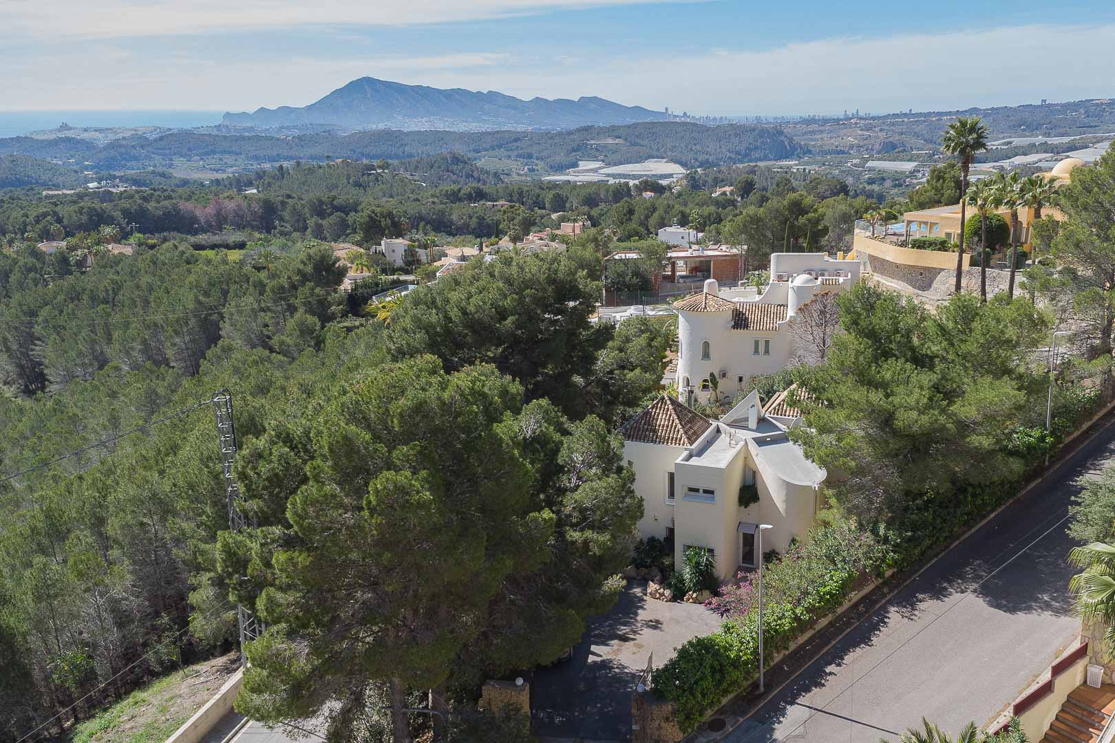 Vue aérienne de la villa nichée dans une pinède, offrant un aperçu de son architecture méditerranéenne avec des vues dégagées sur la mer et les montagnes.
