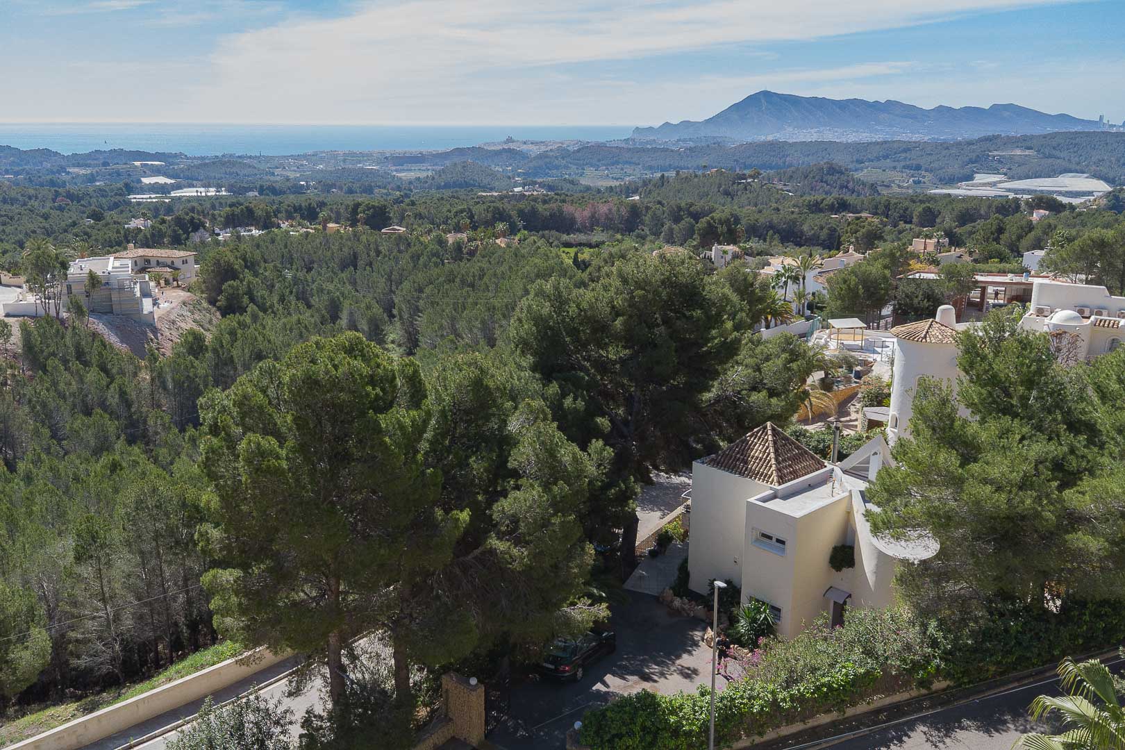 Vue aérienne panoramique de la villa entourée de pins, offrant une perspective dégagée sur la mer Méditerranée et les montagnes environnantes.