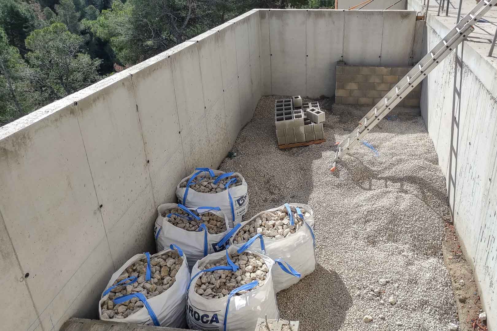 Avancement des travaux montrant les murs en béton armé, le gravier de fondation et les matériaux de construction dans l'environnement naturel d'Altea.