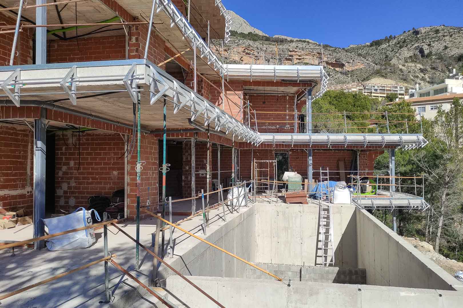 État d'avancement de la villa à Altea, montrant la structure en briques, les dalles en béton et le futur bassin de piscine face à la montagne.