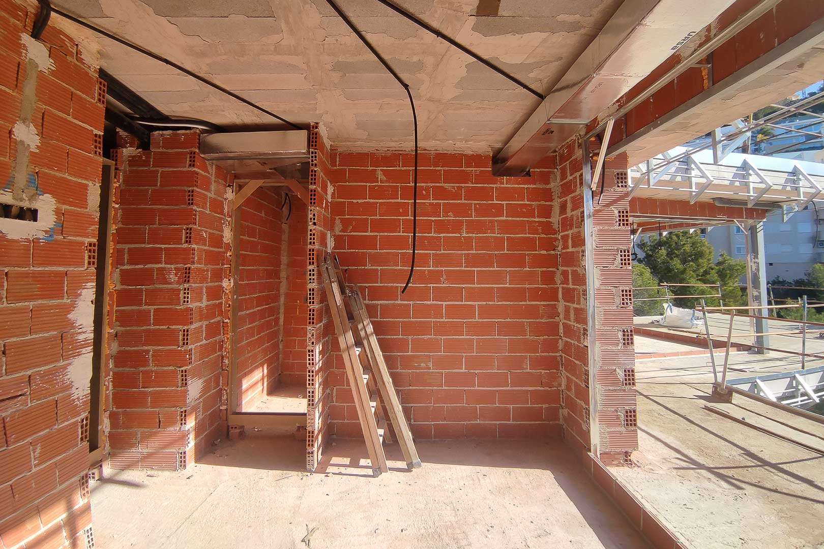 État d'avancement des travaux montrant les cloisons en briques, les dalles en béton et l'installation des conduits de climatisation et du câblage.