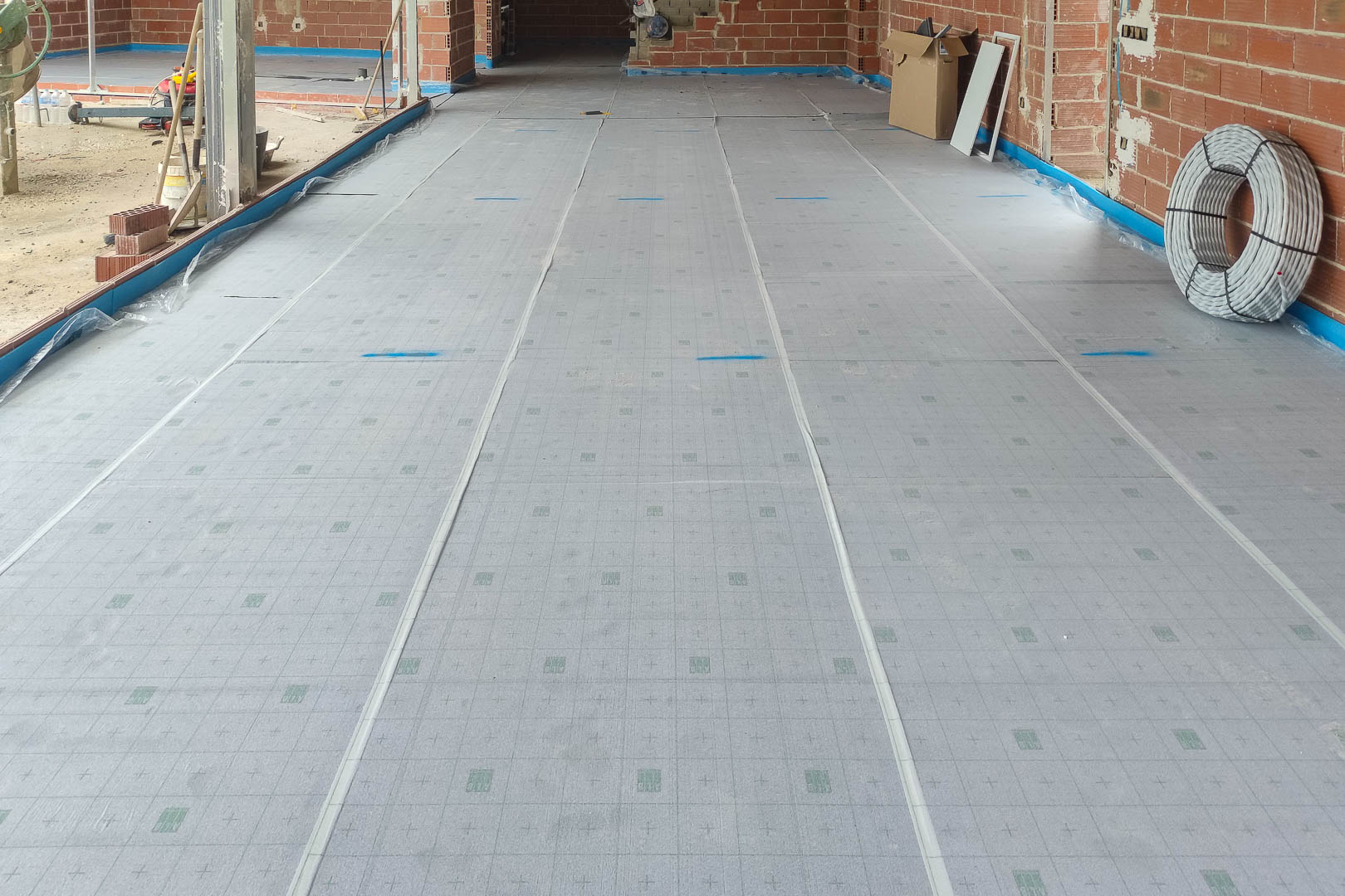 Installation de panneaux isolants thermiques pour le chauffage au sol, illustrant la préparation technique et la qualité des matériaux de construction.