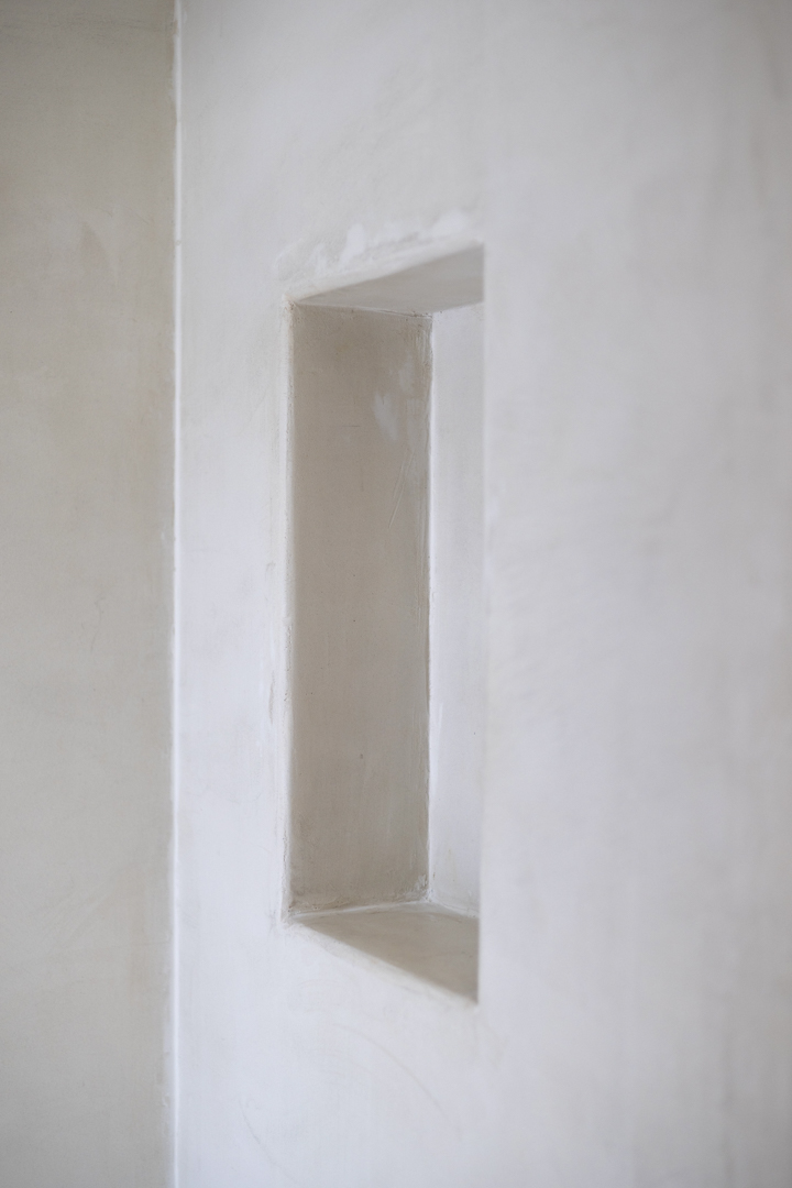 Détail d'une niche rectangulaire dans un mur blanc à texture lisse. Éclairage naturel.