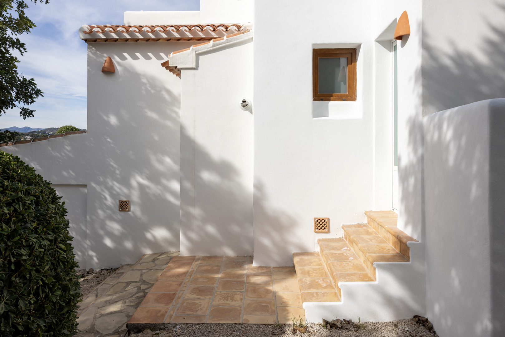 Extérieur de villa à Jávea avec murs blancs, tuiles en terre cuite et escalier d'accès.