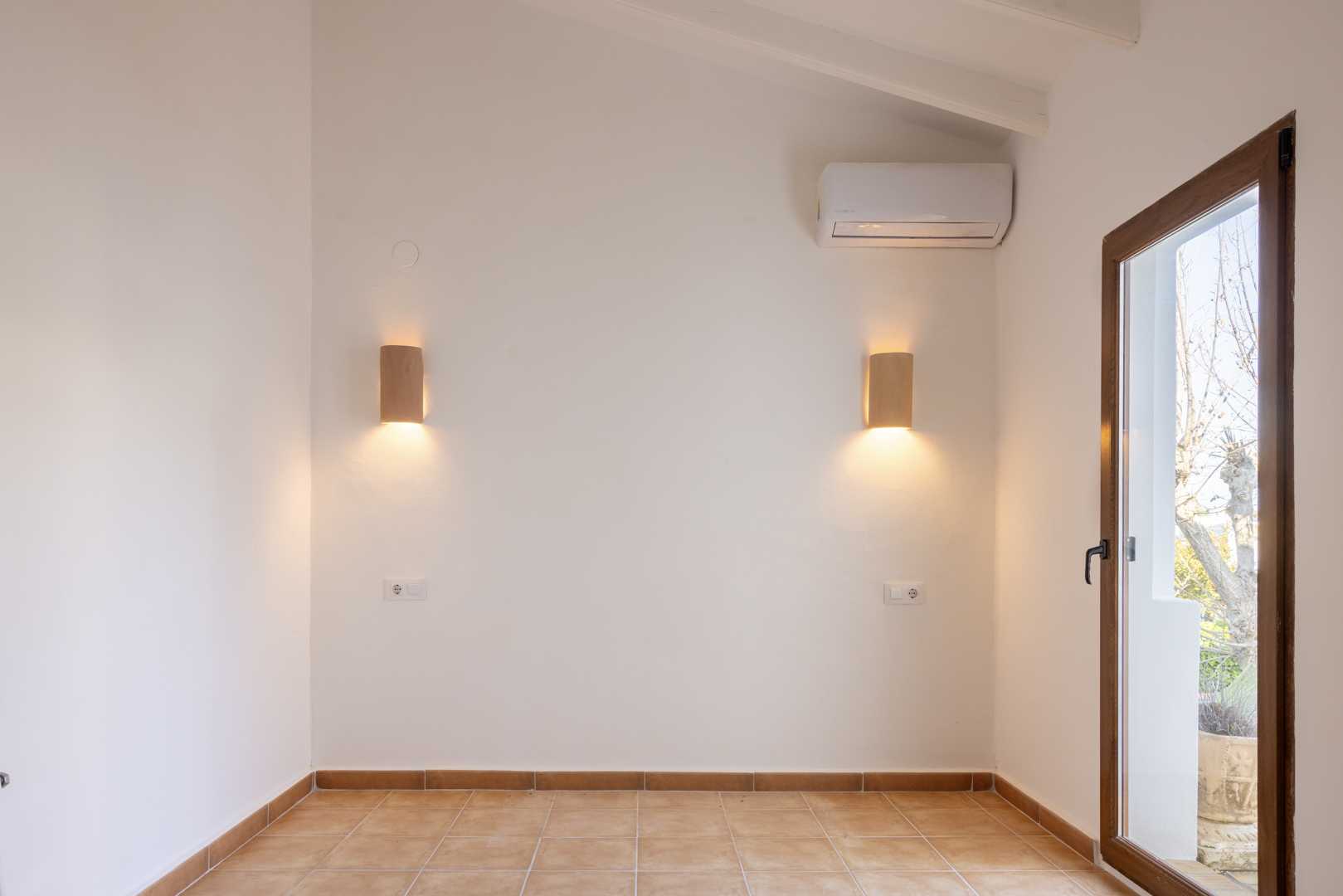 Pièce lumineuse avec appliques en bois et sol carrelé, avec accès à l'extérieur.