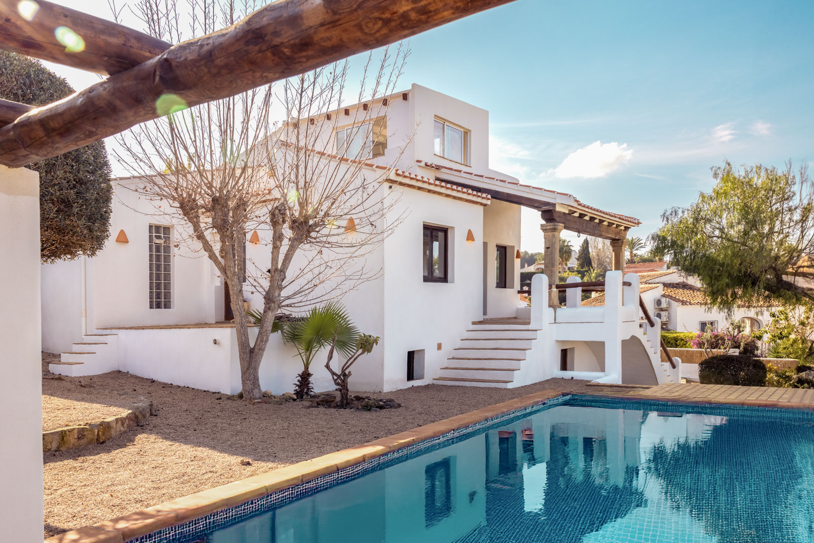 Vue de la villa avec piscine bleu turquoise et façade blanche. Design méditerranéen avec jardin de gravier.