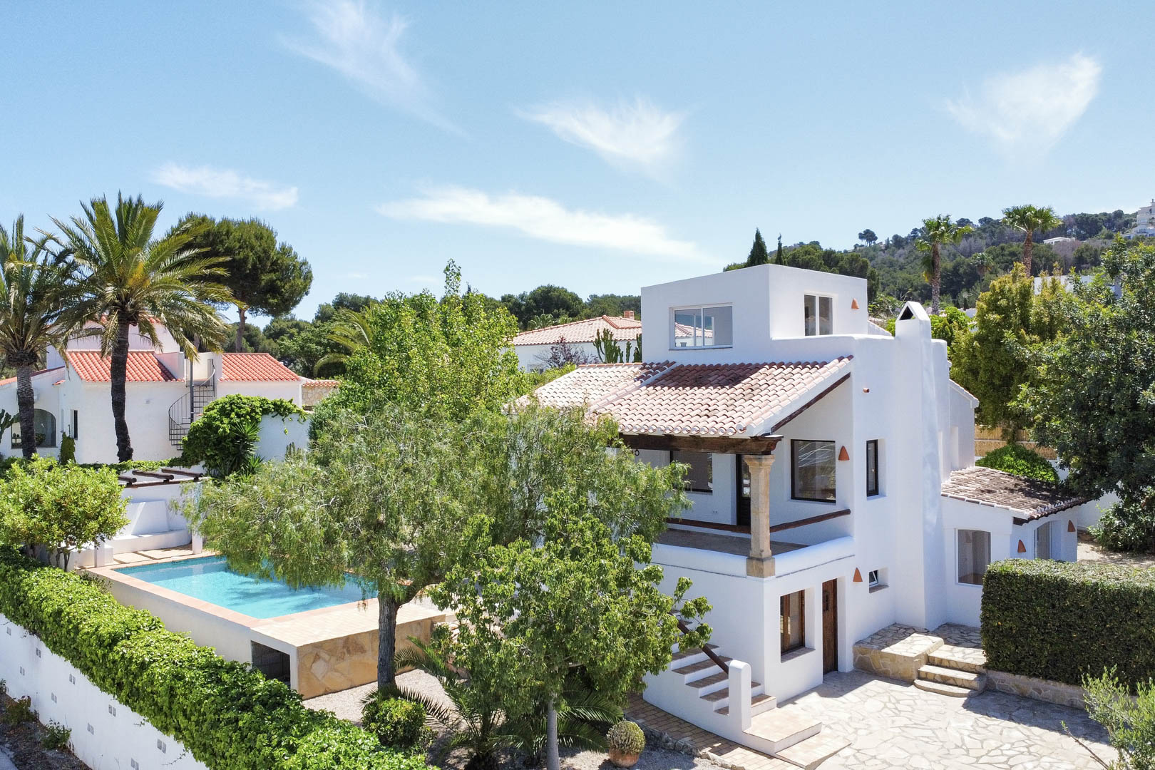 Vue élevée de la villa blanche avec piscine, jardin et toit de tuiles rouges à Jávea.