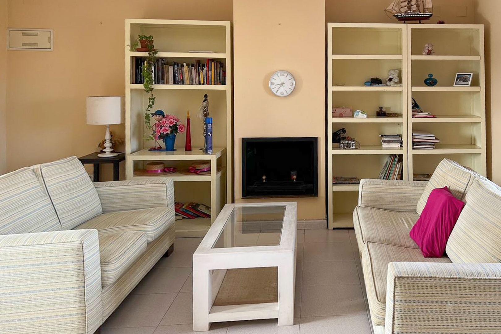 Salon avec canapés rayés, étagères intégrées et cheminée décorative.