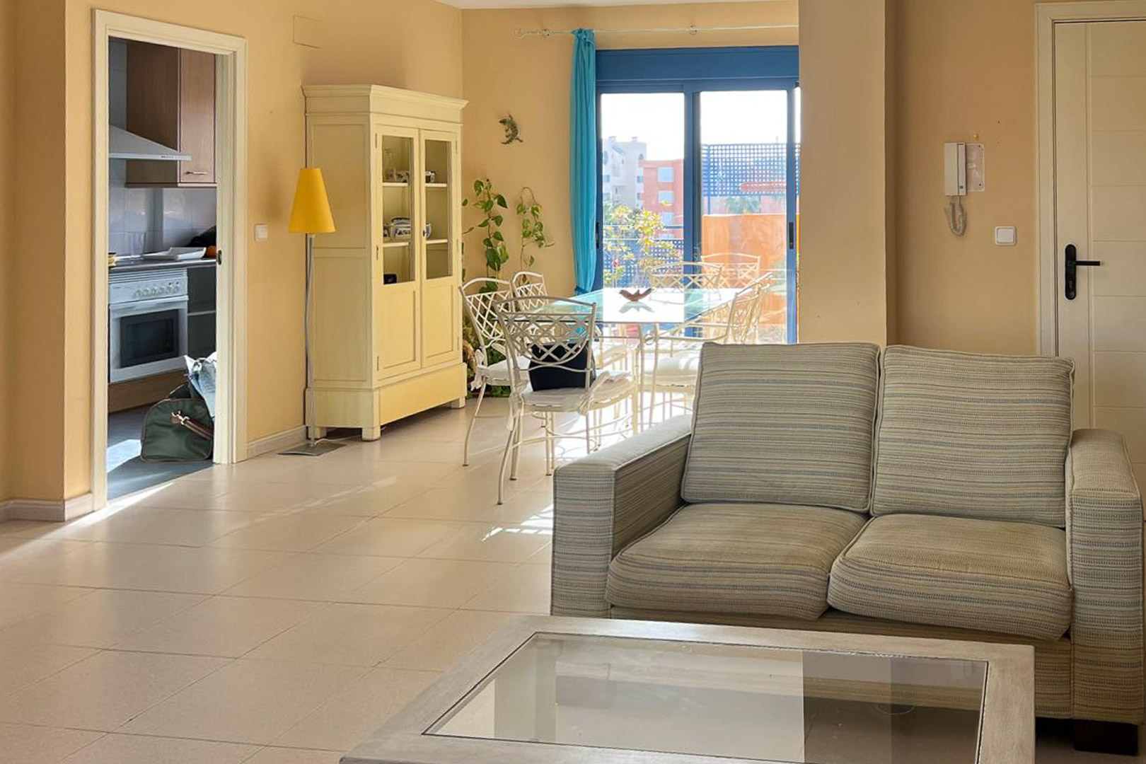 Salon lumineux avec canapé en tissu, table basse et accès à la terrasse.