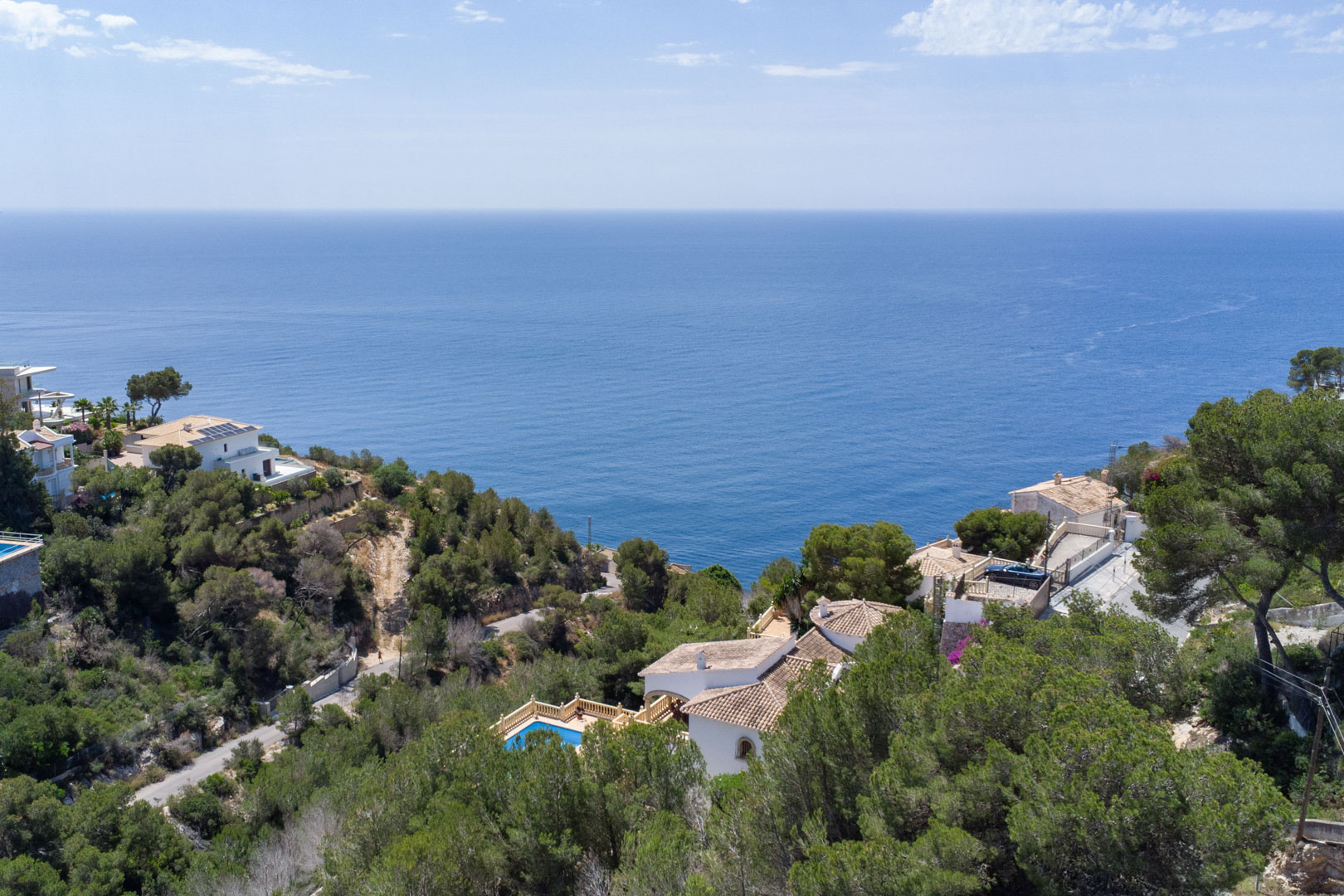 Vue aérienne panoramique sur la mer Méditerranée depuis Costa Nova, illustrant la végétation de pins et les villas situées à proximité de la côte.