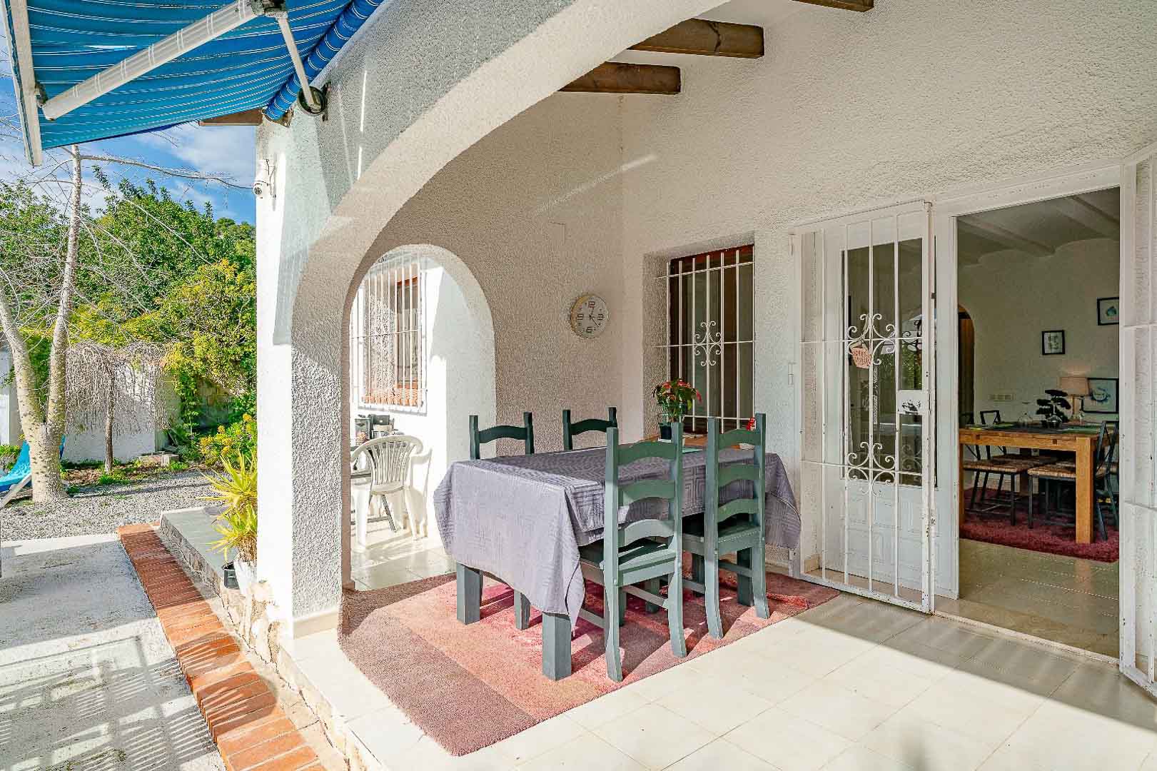 Porche couvert avec arches méditerranéennes, poutres en bois et coin repas. Cet espace relie le jardin à l'intérieur par des portes vitrées sécurisées.