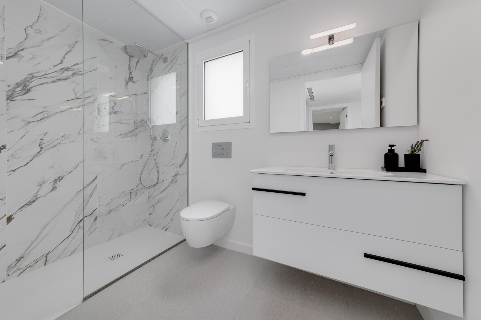 Salle de bain contemporaine avec douche à l'italienne en grès cérame effet marbre, WC suspendu et meuble vasque flottant aux finitions noires.