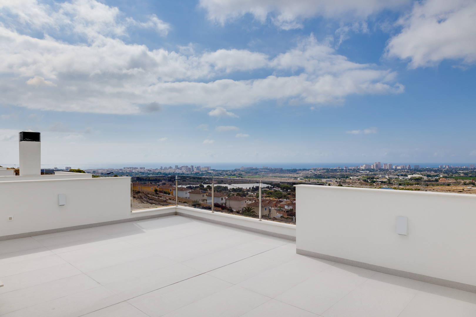 Terrasse supérieure avec carrelage grand format, garde-corps en verre et vues panoramiques sur le littoral et la mer Méditerranée.