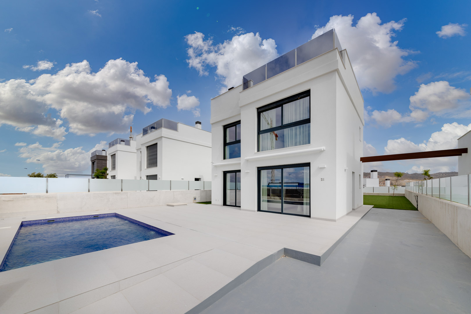 Villa contemporaine blanche avec piscine privée rectangulaire, vaste terrasse dallée et grandes baies vitrées au design minimaliste.