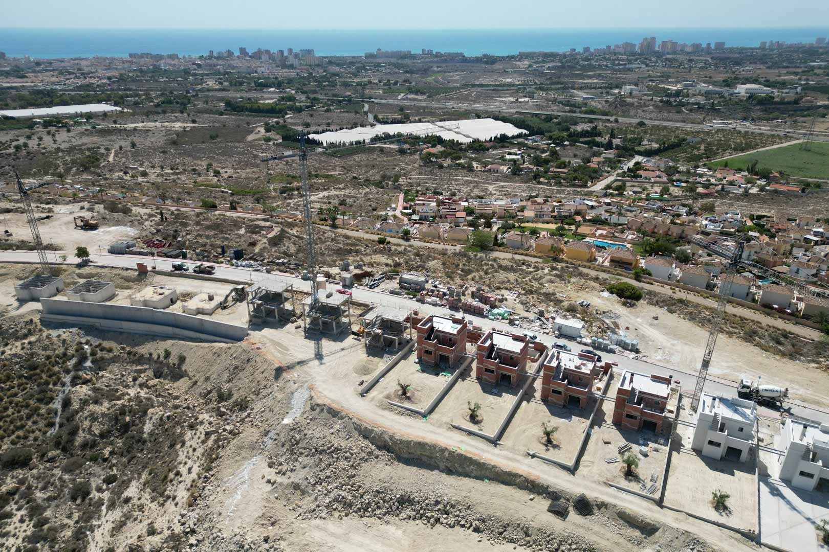 Vue aérienne du chantier de construction sur une colline, illustrant les structures des villas et les vues panoramiques sur la mer Méditerranée et le littoral.
