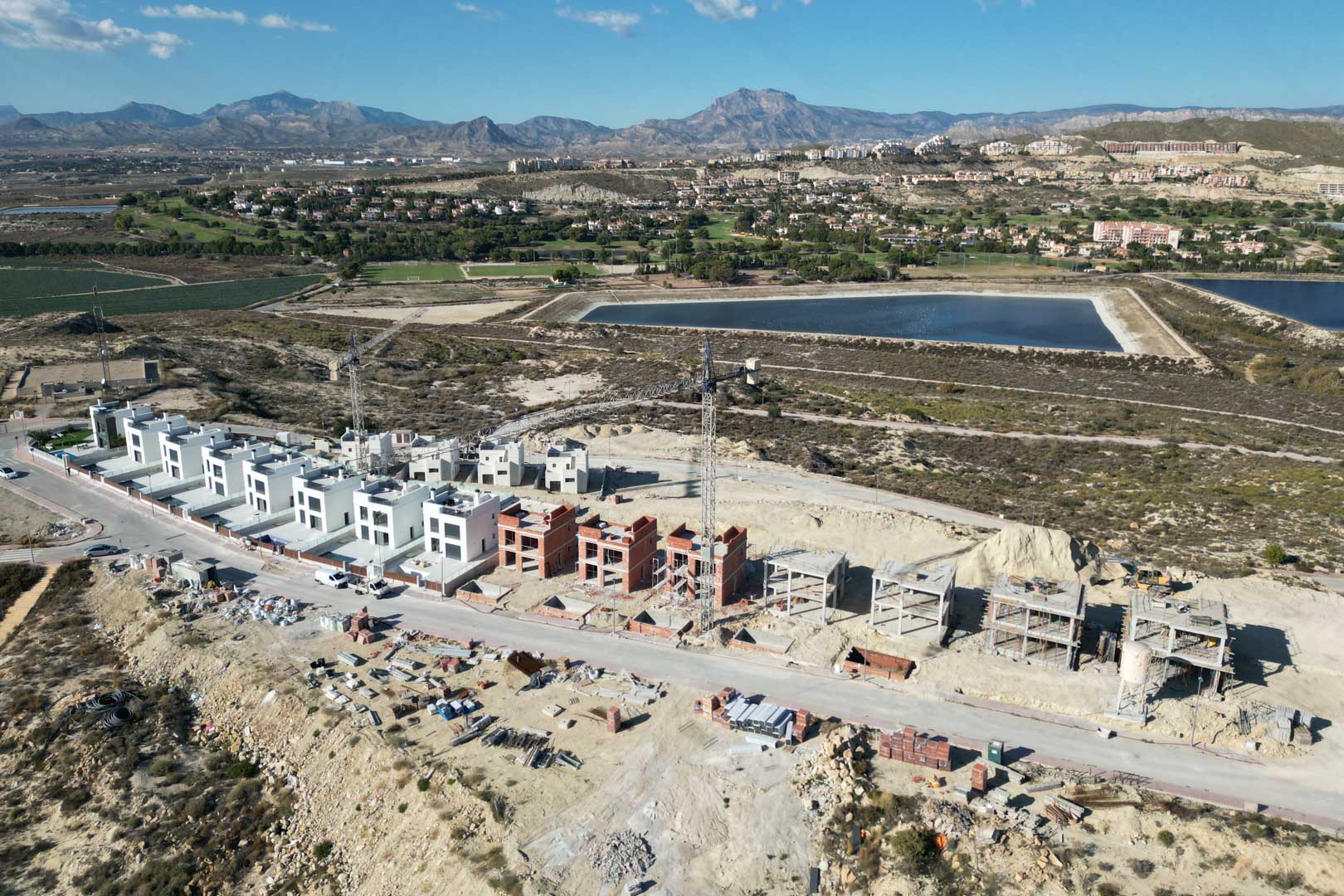 Vue aérienne du projet résidentiel en cours de construction, illustrant les différentes étapes du chantier dans un environnement naturel avec vue sur les montagnes.