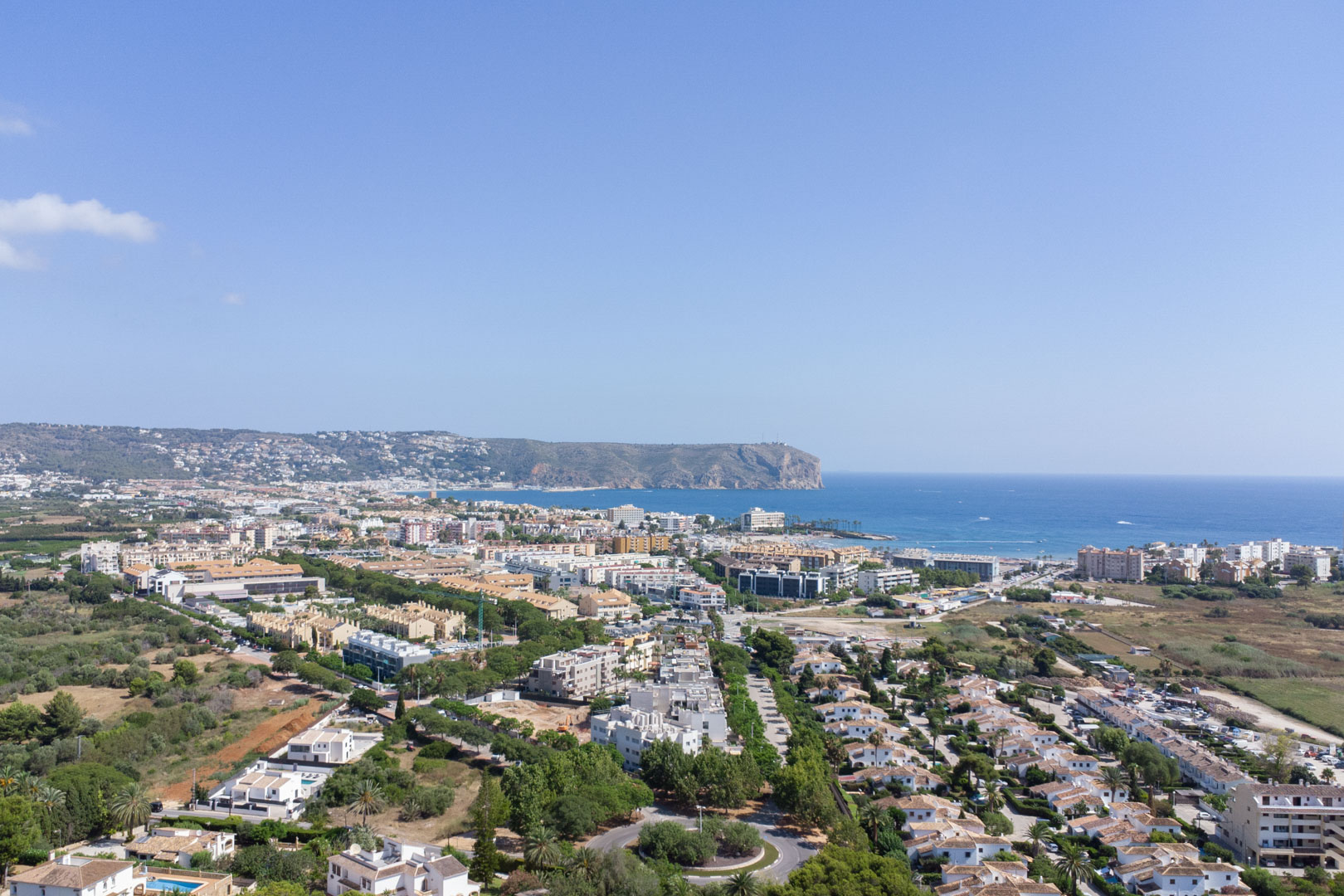 Vue aérienne panoramique de Jávea illustrant la proximité de la mer Méditerranée et de l'emblématique Cabo de San Antonio par temps clair.