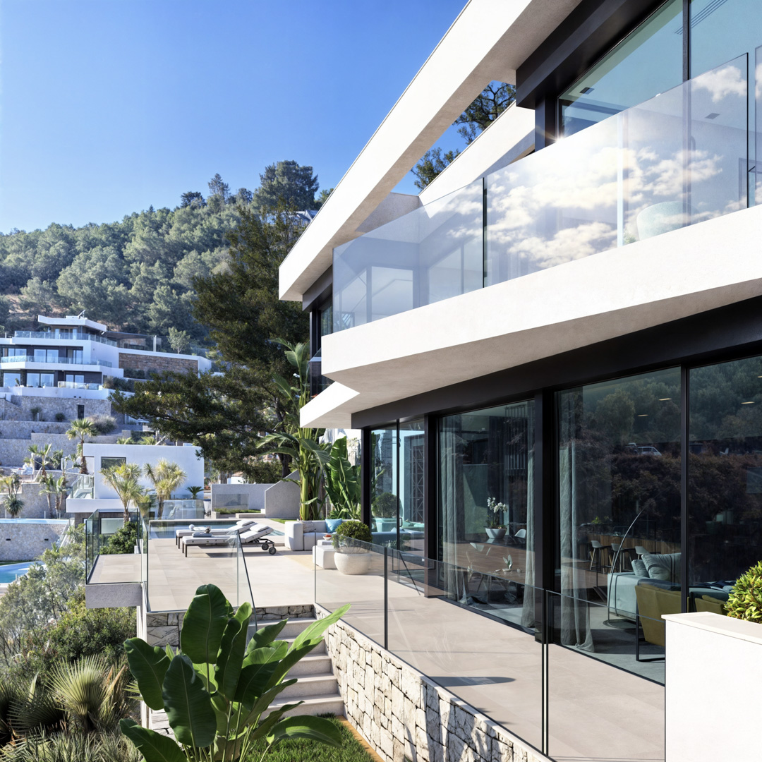Façade moderne aux terrasses blanches en porte-à-faux, garde-corps en verre et larges baies vitrées. Les murs en pierre naturelle s'intègrent harmonieusement au jardin méditerranéen.