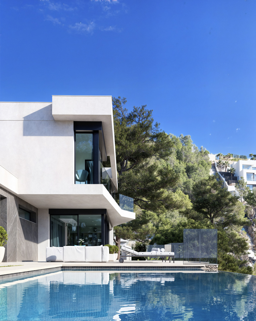Vue extérieure avec piscine à débordement, façade minimaliste en stuc blanc et pierre grise, et grandes baies vitrées entourées d'une pinède naturelle.