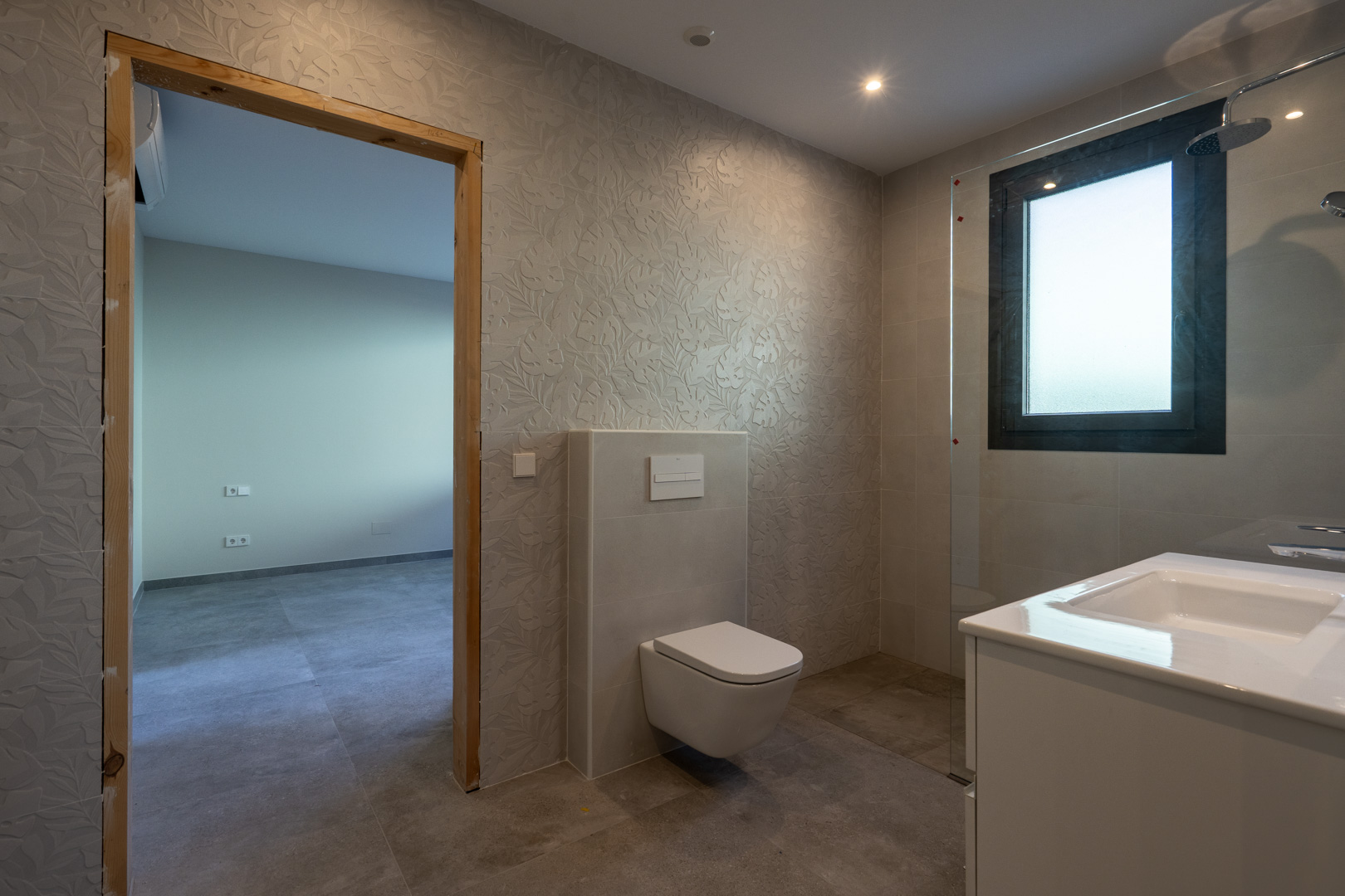 Détail d'une salle de bain moderne avec murs texturés et douche vitrée.