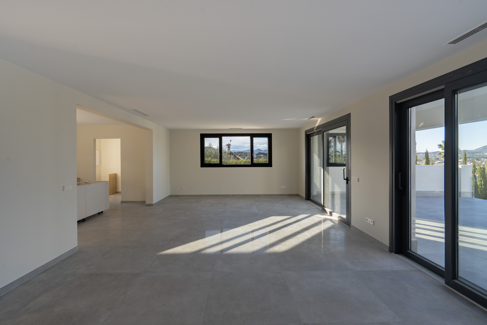 Salon spacieux avec carrelage, fenêtre panoramique et accès à la terrasse à Jávea.