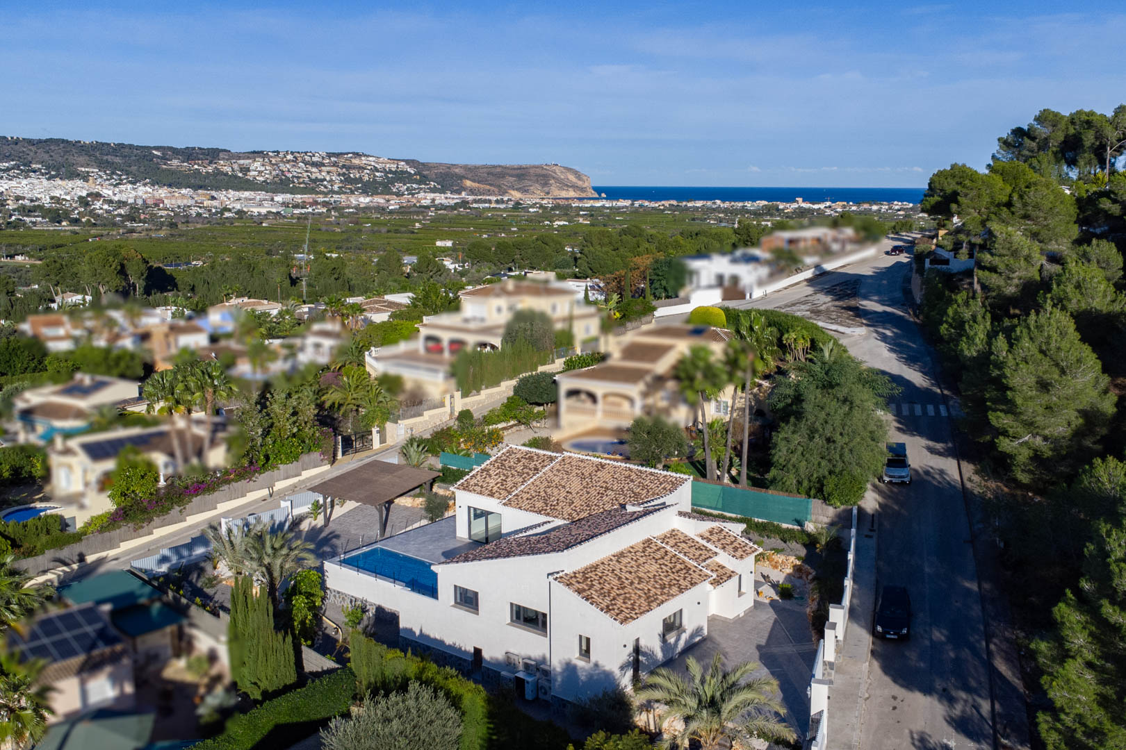 Vue aérienne d'une villa moderne avec piscine à Jávea, entourée de jardins et avec vue sur la mer.