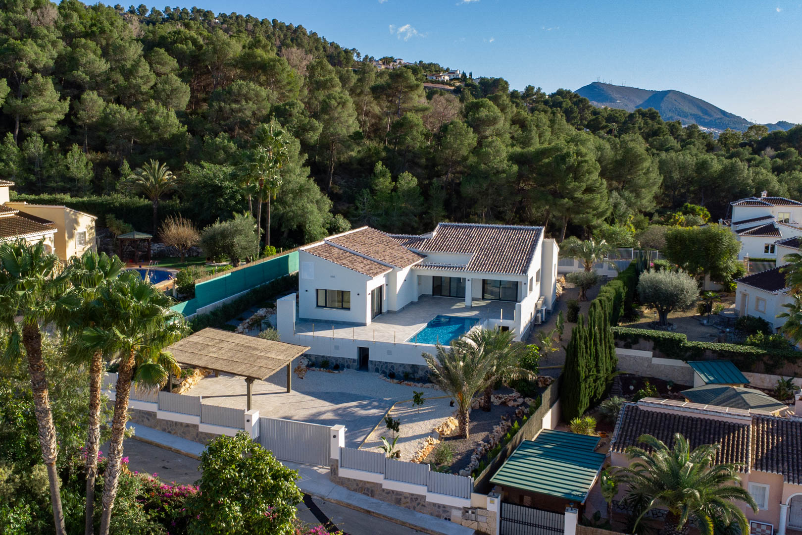 Vue aérienne d'une villa moderne avec piscine, entourée d'une végétation luxuriante et d'un parking couvert à Jávea.