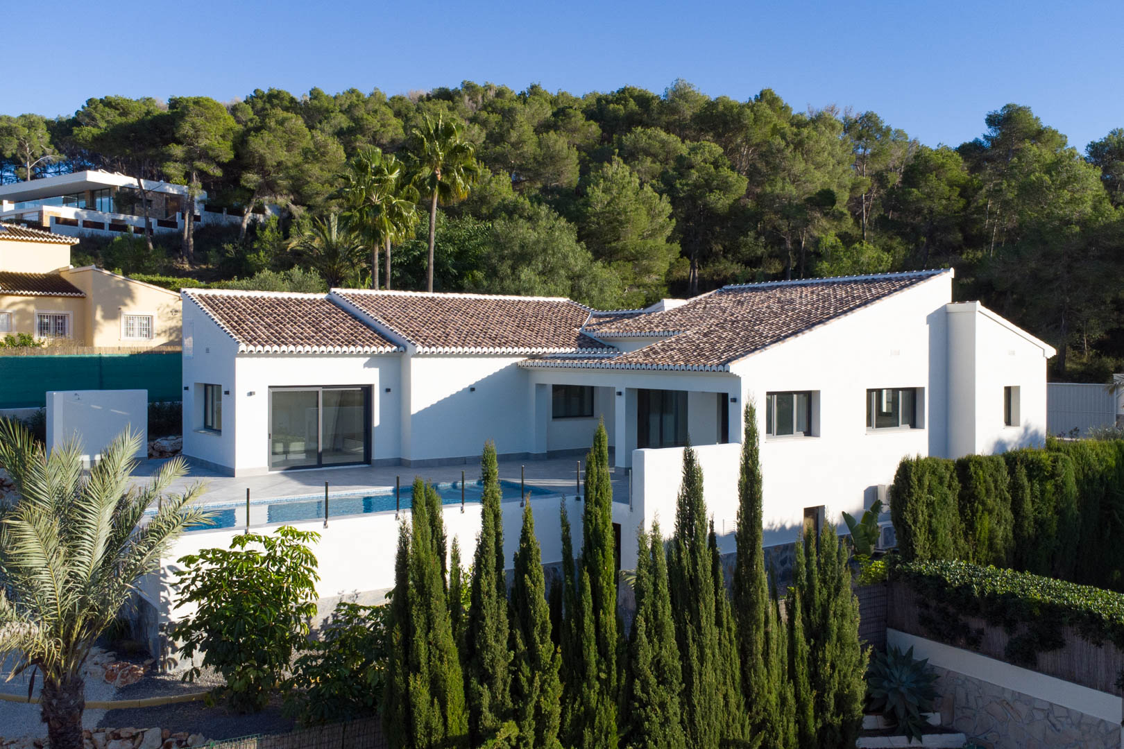 Vue extérieure de la villa à Piver, Jávea, mettant en valeur son design moderne, sa piscine privée et son environnement naturel luxuriant.