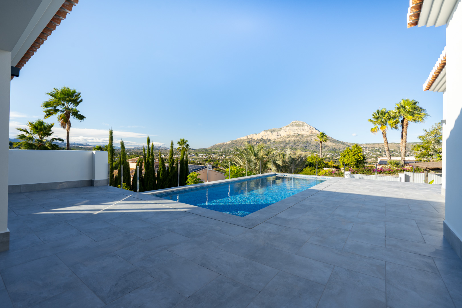 Vue sur la piscine privée avec carrelage gris et paysage montagneux à Jávea.
