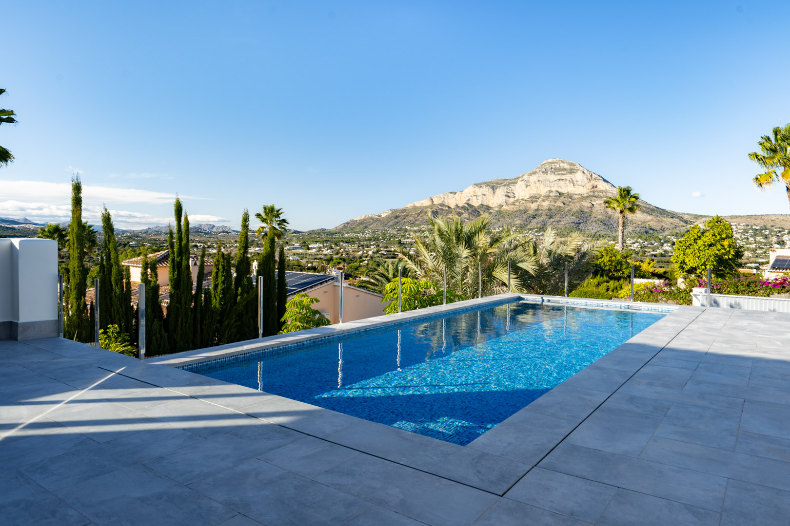 Vue sur la piscine privée avec des carreaux bleus et une bordure grise, offrant une vue panoramique sur la montagne et le paysage.