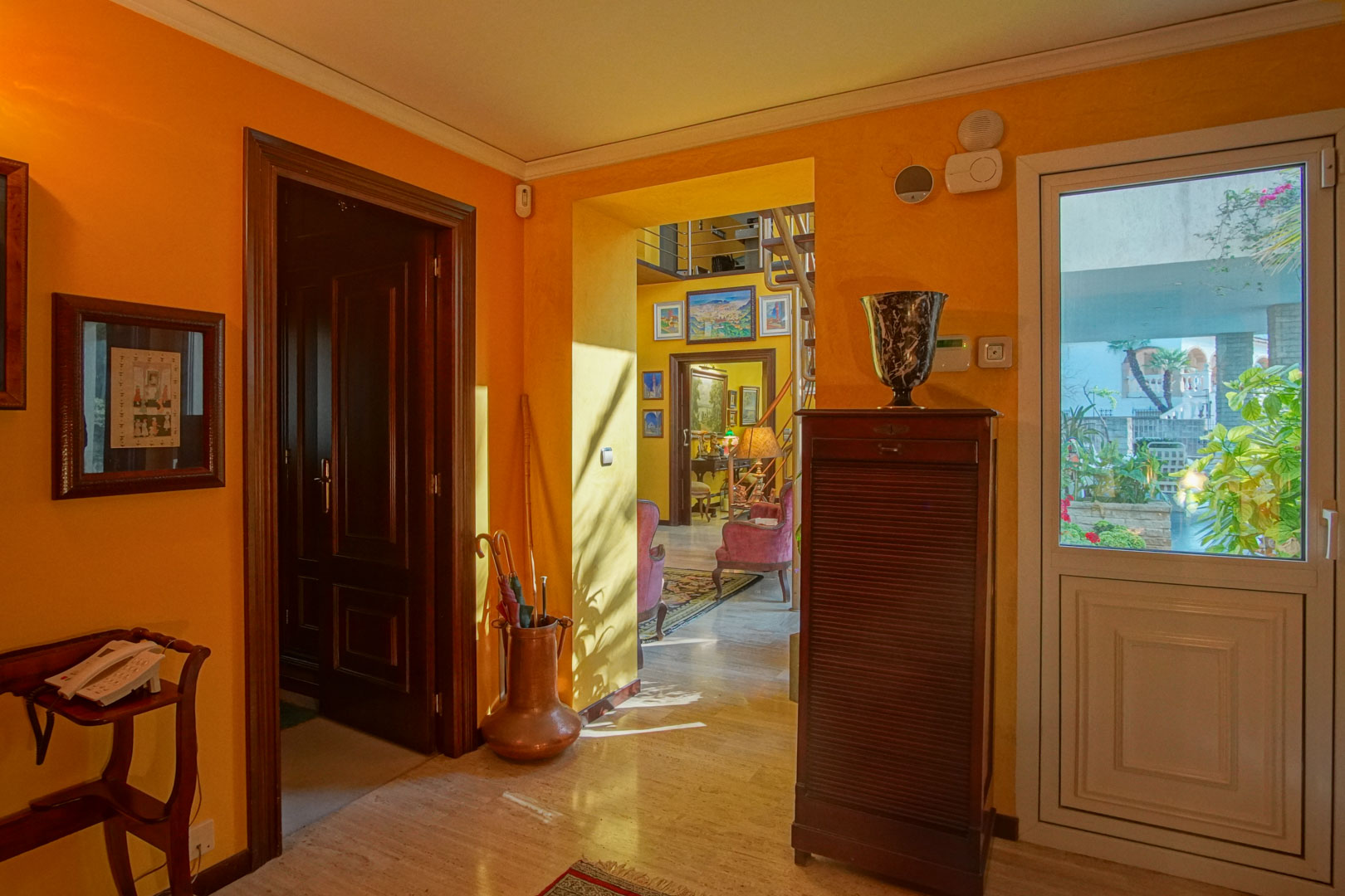 Hall d'entrée avec sols en marbre poli, murs aux tons chauds et menuiseries en bois sombre. Accès direct au salon et luminosité naturelle traversante.