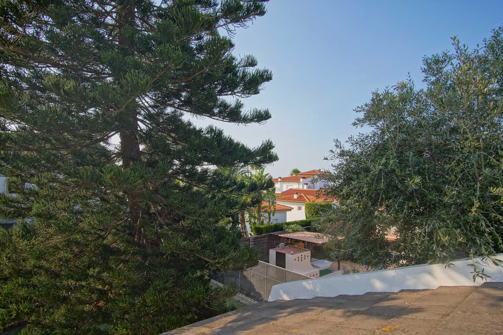 Vue surélevée depuis la terrasse mettant en valeur la végétation méditerranéenne et les toits en terre cuite des villas voisines.