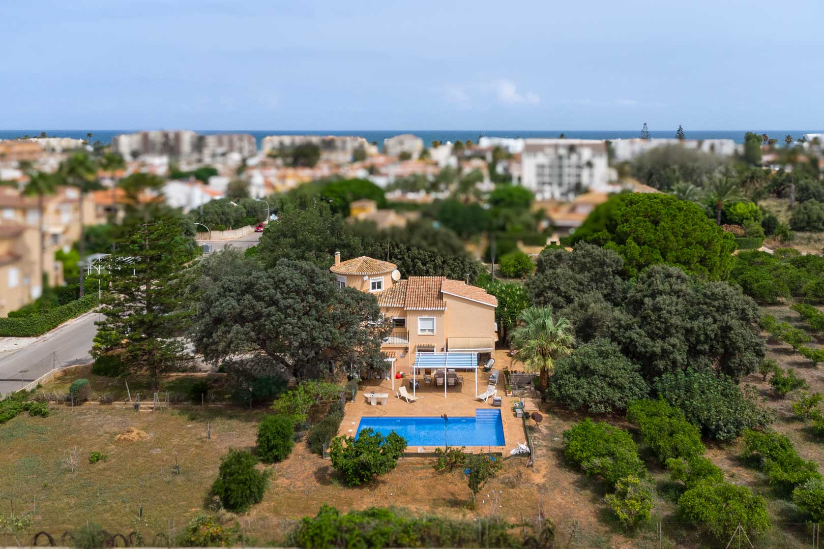 Vue aérienne de la villa méditerranéenne à Las Marinas, montrant son grand terrain plat avec piscine, terrasses ombragées et la mer à l'horizon.