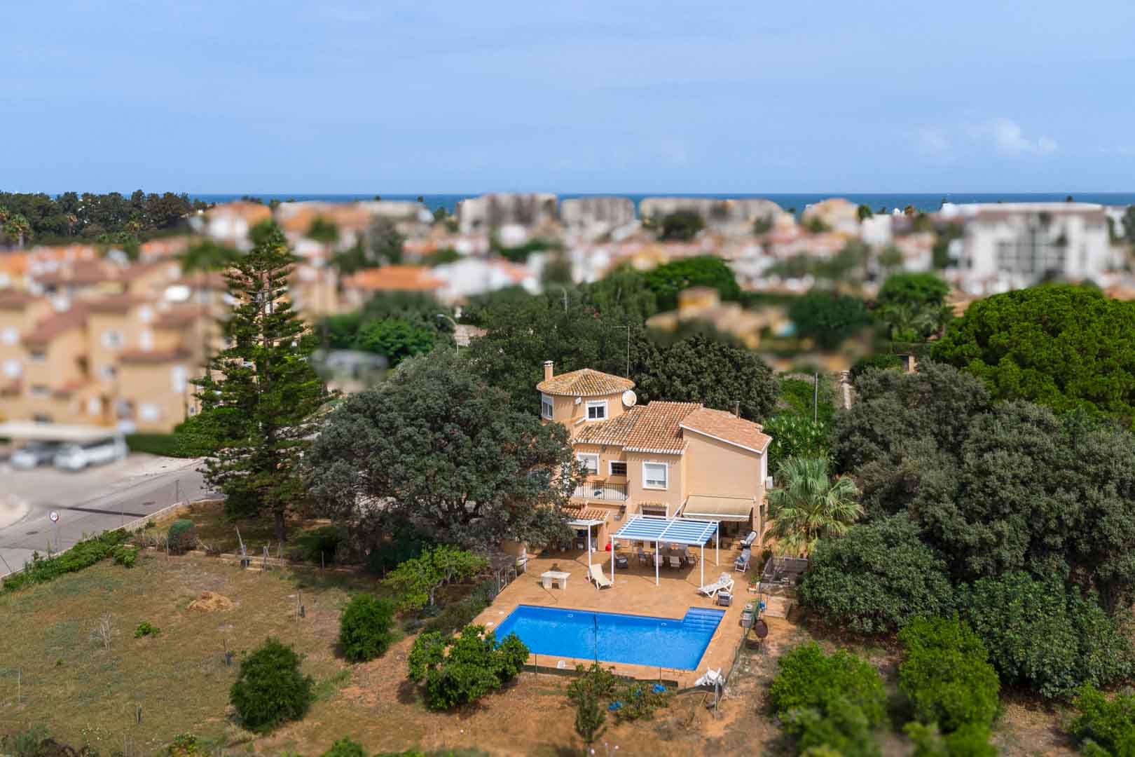 Vue aérienne de la villa méditerranéenne illustrant la piscine privée, les terrasses ombragées et le vaste terrain plat arboré à proximité du littoral.