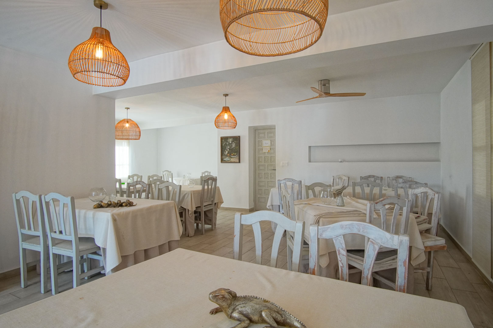 Salle à manger lumineuse du restaurant avec tables dressées et chaises en bois peintes.