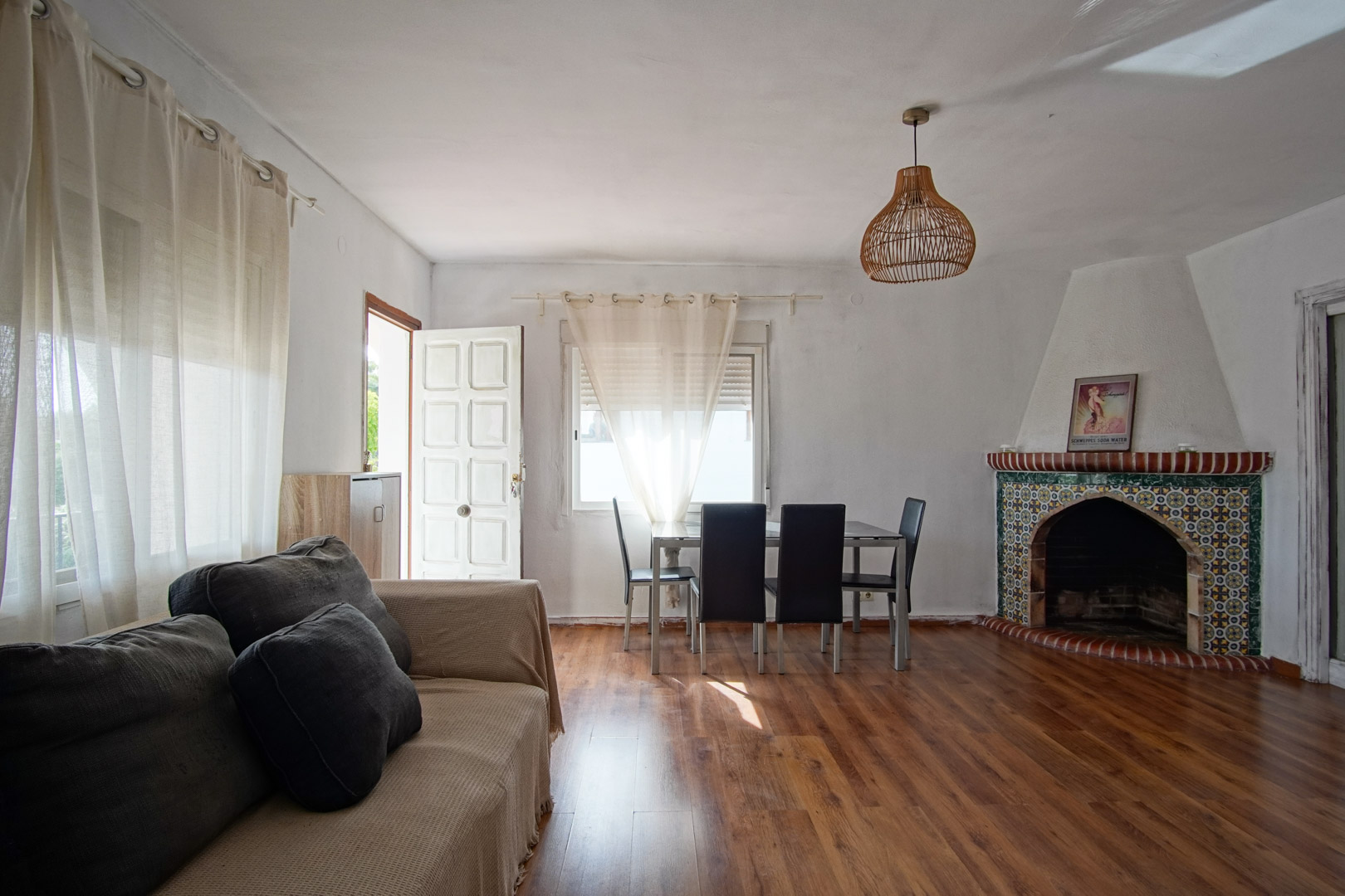 Salon-salle à manger avec cheminée en faïence et mobilier fonctionnel.