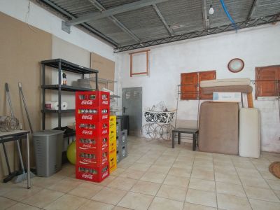Espace intérieur avec étagères métalliques, caisses de soda empilées et divers objets sur un sol carrelé.