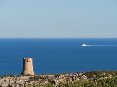 Vue sur la mer Méditerranée depuis Las Rotas avec une tour en pierre et des navires à l'horizon.