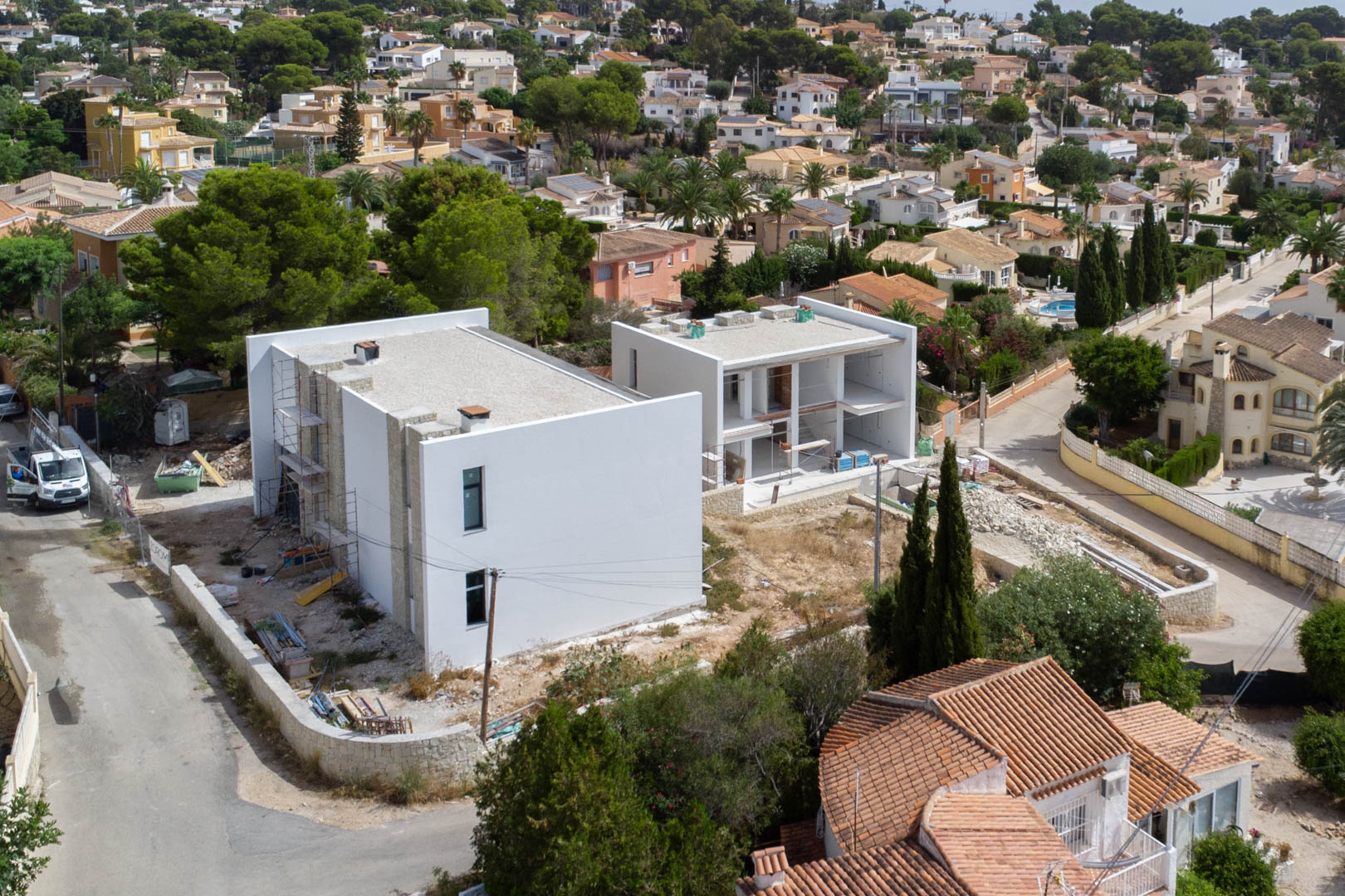 Vue aérienne de la phase de construction, montrant la structure moderne avec des murs blancs et des détails en pierre naturelle dans le quartier de La Merced.