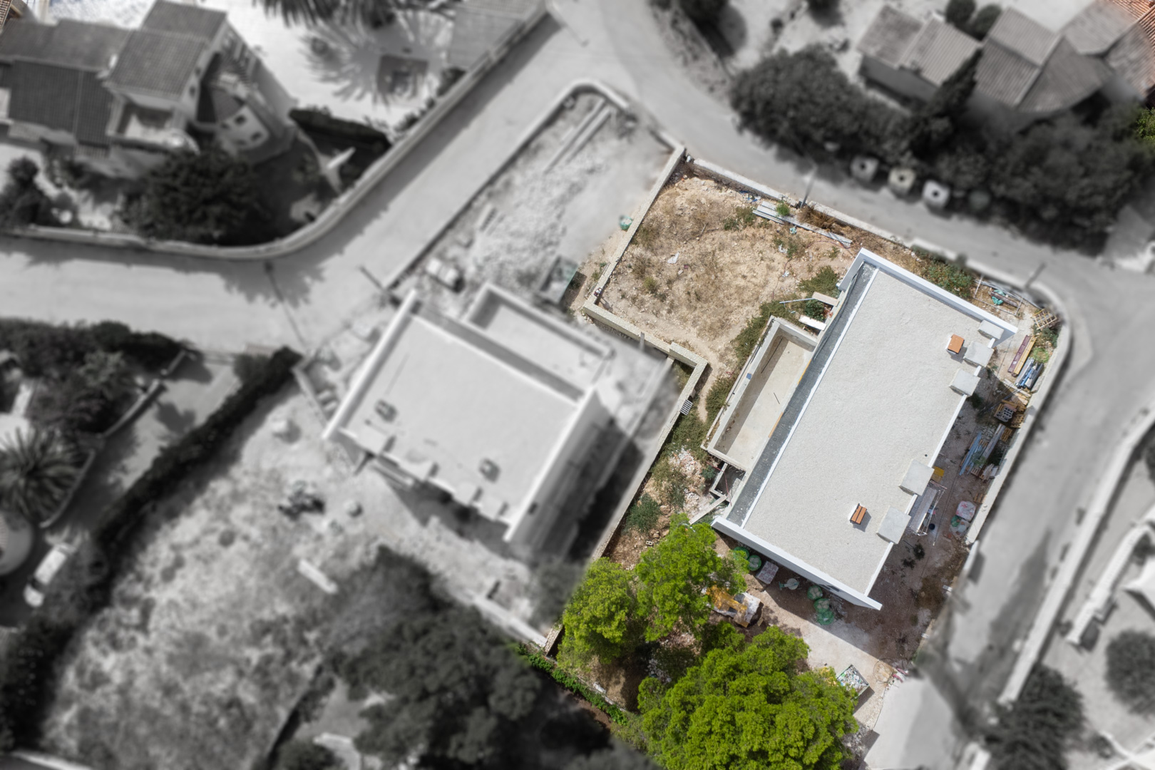 Vue aérienne montrant l'état d'avancement de la construction, la structure de la villa, l'emplacement de la piscine et la configuration du terrain plat.