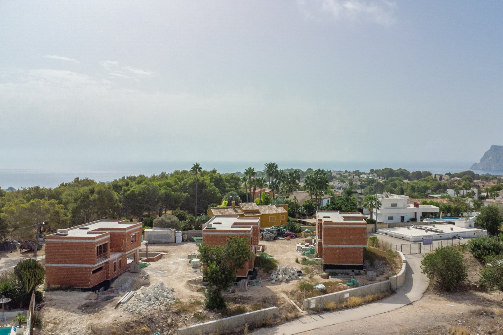 Vue aérienne de l'état d'avancement des trois villas de luxe, illustrant les structures en briques et le panorama sur la mer Méditerranée et le Peñón de Ifach.